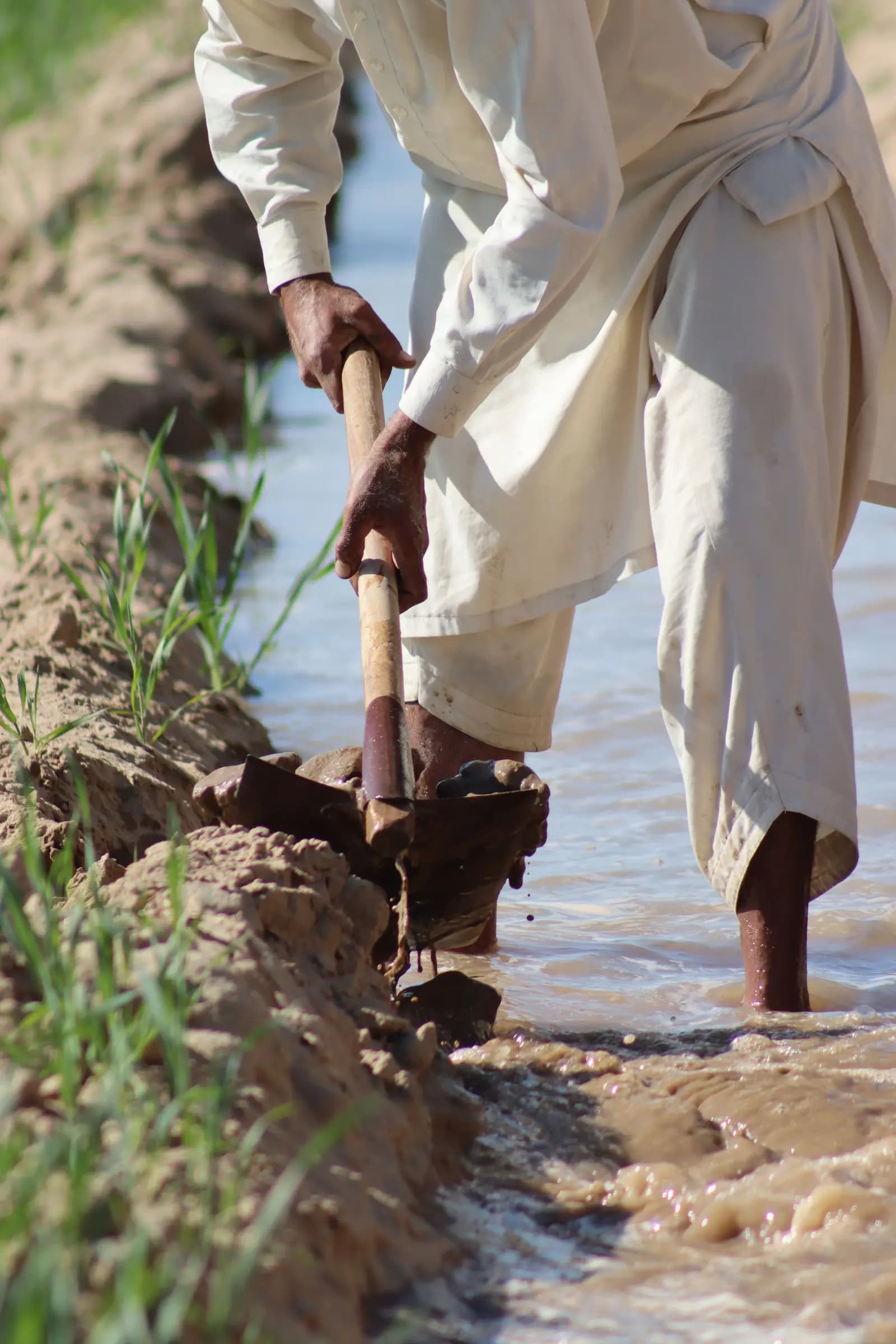 Homme manœuvrant une vanne dans un canal d'irrigation traditionnel